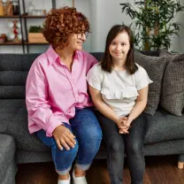 A woman with short curly reddish hair sitting on a grey couch