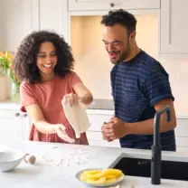 A smiling man and woman playfully preparing dough together