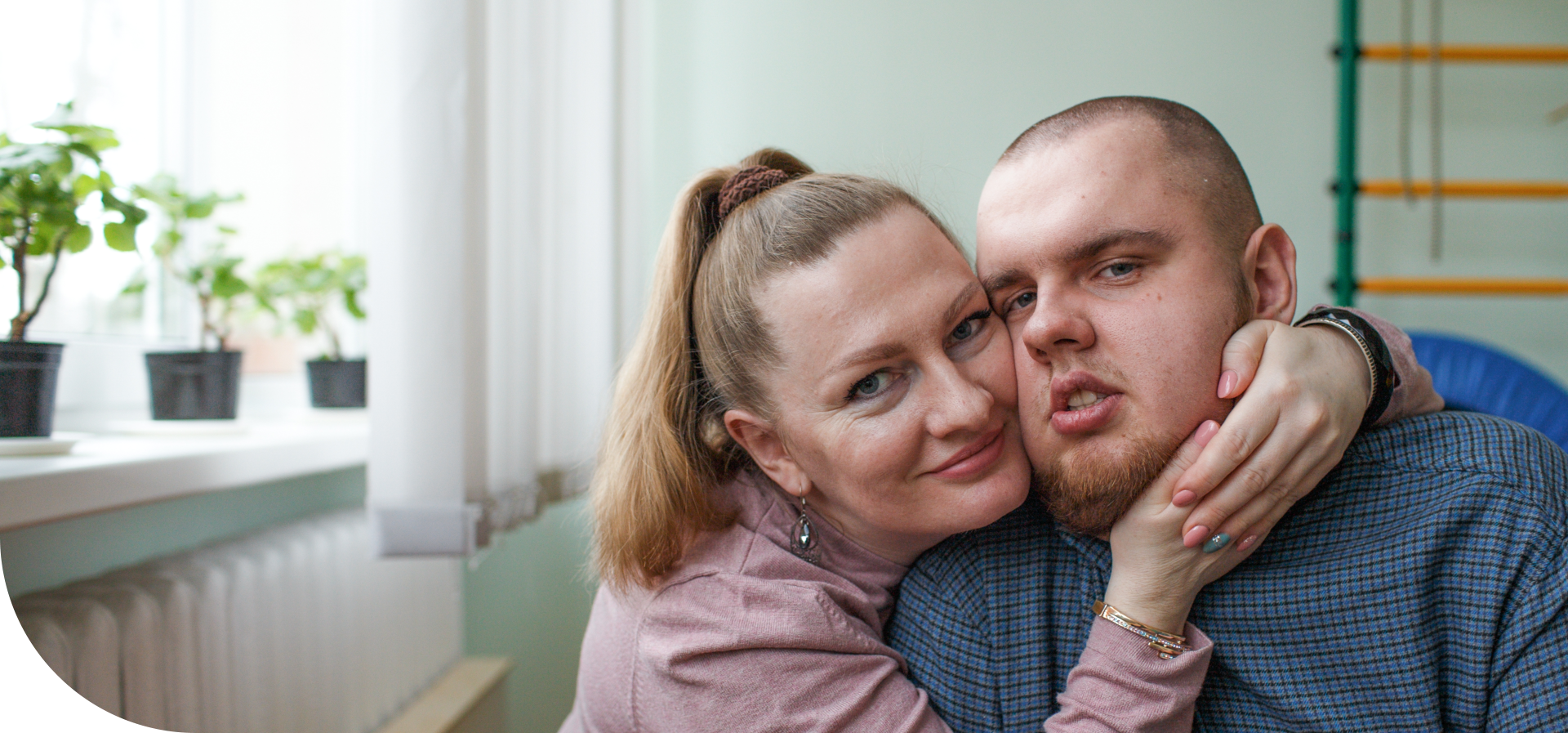 A woman leaning her face lovingly against a young man wearing a blue shirt
