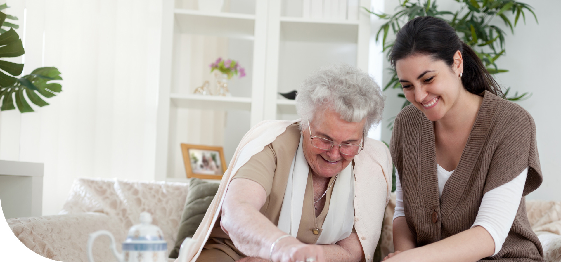 A young caregiver or family member smiling while spending time with an elderly woman