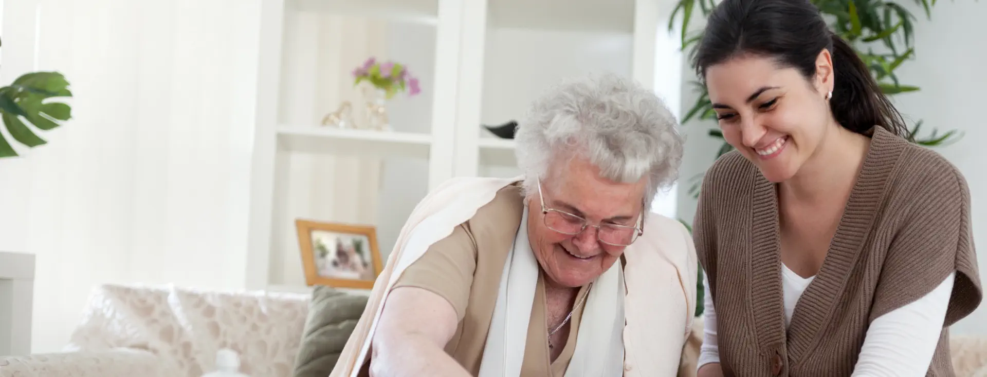 A young caregiver or family member smiling while spending time with an elderly woman
