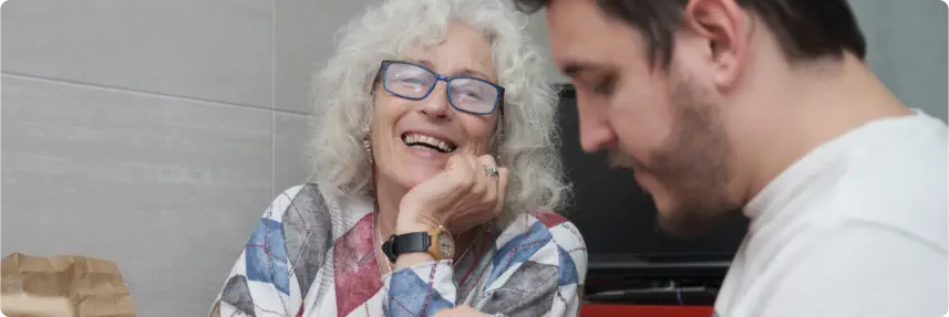 Mature mother laughing while is in the kitchen with her adult son