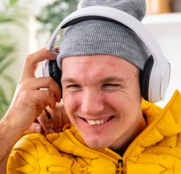 Smiling person wearing headphones and a yellow jacket