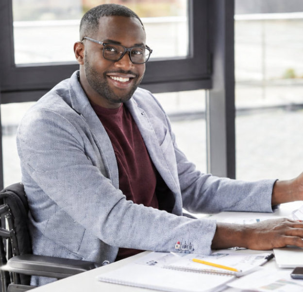 Smiling man in a wheelchair working at a desk