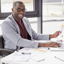 Smiling Man in Wheelchair Working at White Desk