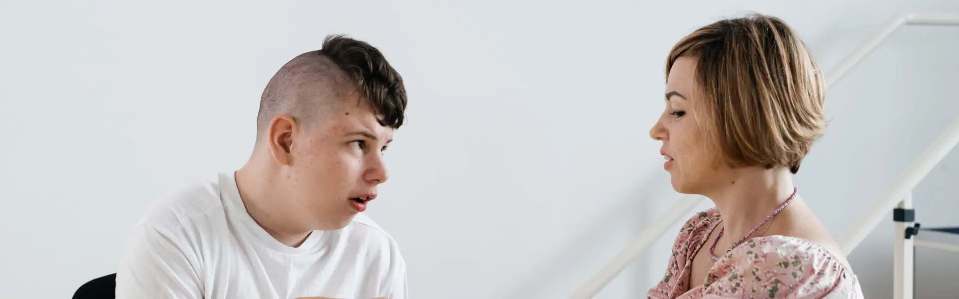 young man with a shaved hairstyle on the sides looking towards a woman