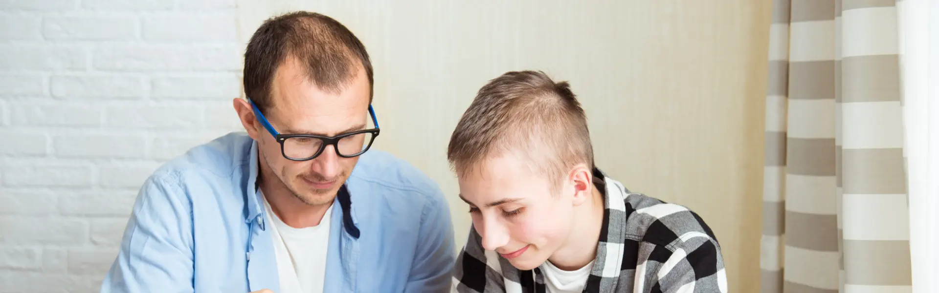 father wearing glasses sitting alongside his son